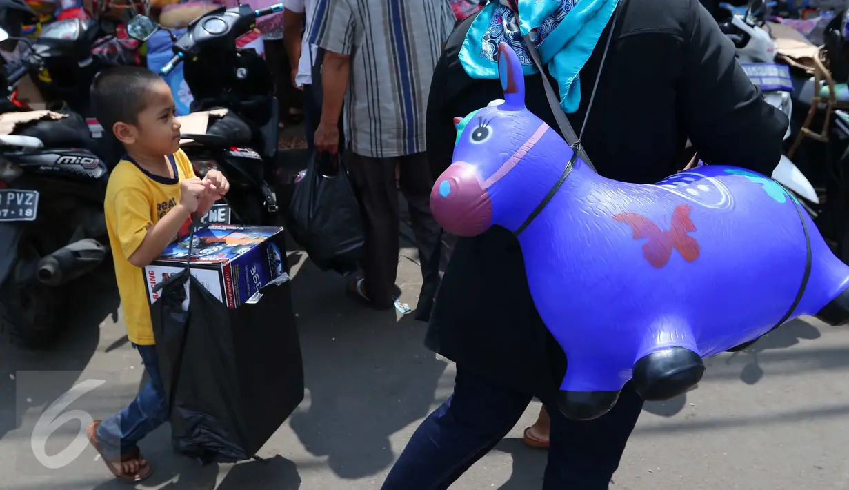Seorang anak membawa kantong plastik berisi mainan yang dibelinya di Pasar Gembrong, Jakarta, Jumat (8/7). Libur lebaran banyak dimanfaatkan orang tua untuk mengajak anaknya berbelanja aneka mainan murah. (Liputan6.com/Angga Yuniar)