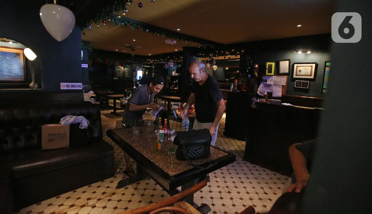 Pegawai bersama warga negara asing membersihkan sisa-sisa banjir di salah satu bar di kawasan Kemang Raya, Jakarta, Kamis (2/1/2020). Para pegawai mulai membersihkan ruangan yang terendam air pascabanjir yang melanda Kemang Raya. (Liputan6.com/Herman Zakharia)