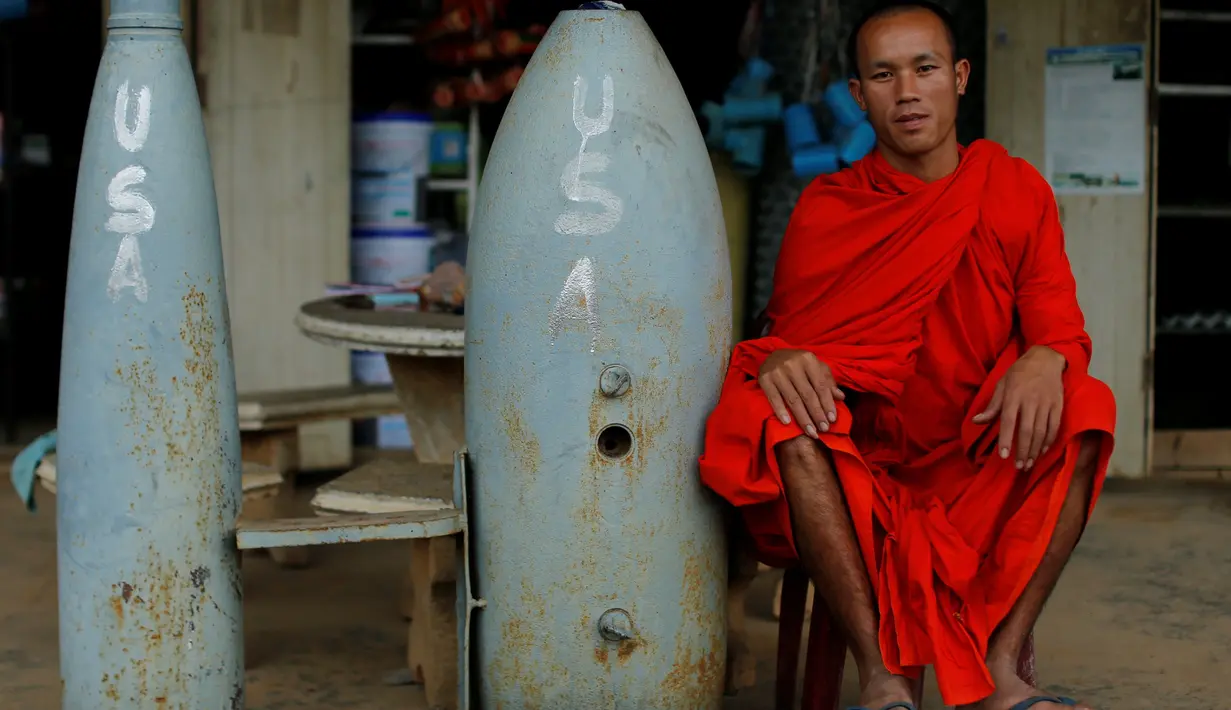 Seorang  biksu Buddha duduk di samping bom yang belum meledak dijatuhkan oleh pesawat-pesawat Angkatan Udara AS selama Perang Vietnam, di Provinsi Xieng Khouang, Laos (03/9). (REUTERS/Jorge Silva)
