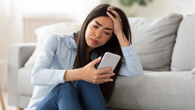 perempuan stres memegang ponsel
