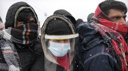 Migran menunggu untuk dipindahkan selama hujan salju di kamp Lipa, barat daya Bosnia, dekat perbatasan dengan Kroasia, Sabtu (26/12/2020). Ratusan migran terdampar di tenda-tenda kumuh dan terbakar di Bosnia, di tengah hujan salju yang lebat dan suhu membeku. (AP Photo/Kemal Softic)