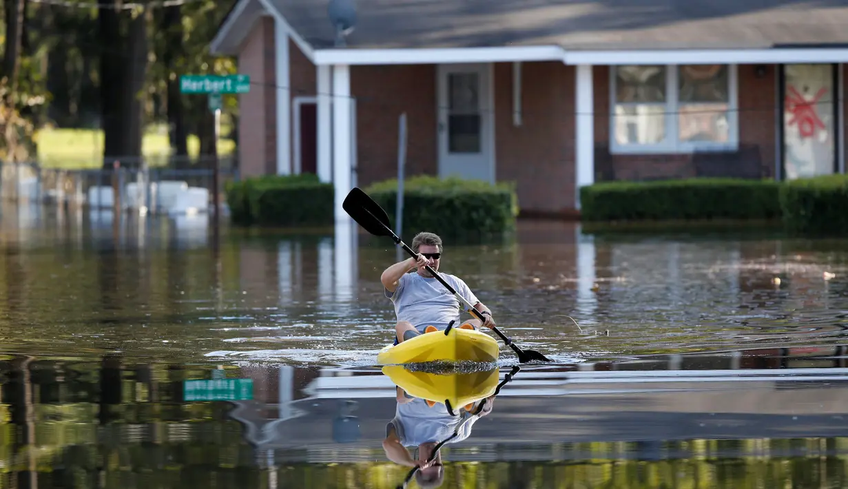 Parker Uzzell mendayung kano untuk aktivitas di tengah banjir yang melanda wilayah Lumberton di Carolina Utara, Amerika Serikat, 12 Oktober 2016. Banjir akibat badai Matthew tersebut merendam kota berpenduduk 21.000 orang itu. (REUTERS/Randall Hill)