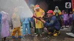 Petugas pemadam kebakaran (Damkar) Kota Tangerang membantu siswa Taman Kanak-Kanak (TK) menyemprotkan air untuk memadamkan api saat edukasi pengenalan profesi Damkar di Kota Tangerang, Banten (22/11/2023). (Liputan6.com/Angga Yuniar)