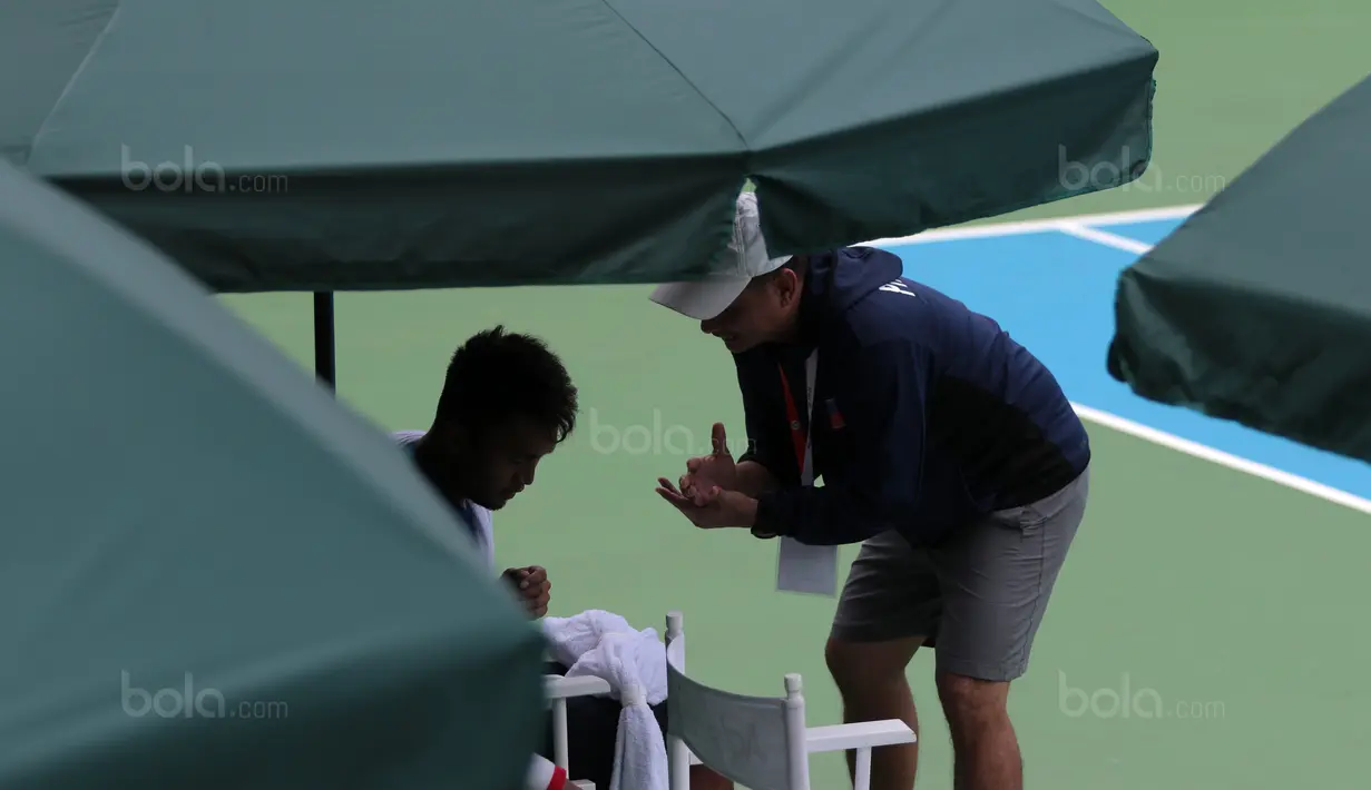 Petenis Filipina, Jeson Patrombon menerima arahan dari sang pelatih pada Piala Davis 2018 grup dua Asia/Oceania di Senayan, Jakarta, Sabtu (3/2/2018). David menang 6-2, 7-5. (Bola.com/Nick Hanoatubun)