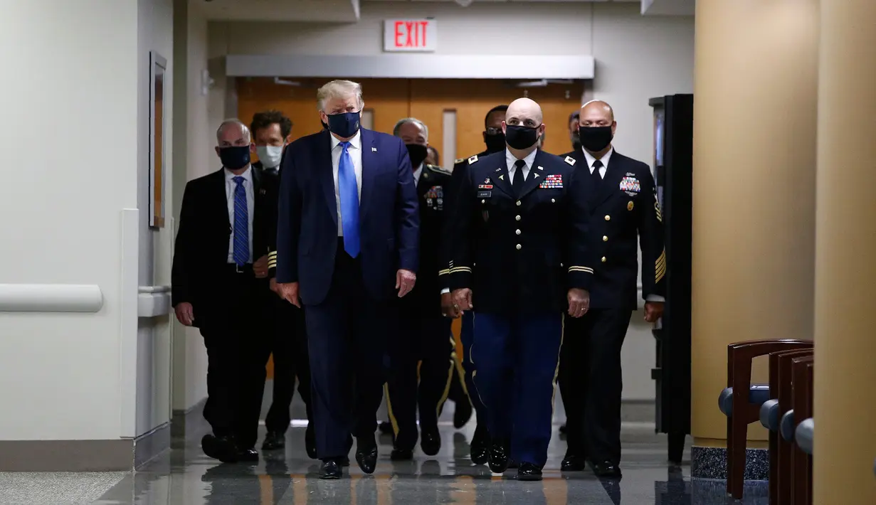Presiden Amerika Serikat Donald Trump mengenakan masker saat menyusuri lorong dalam kunjungannya ke Pusat Kesehatan Militer Nasional Walter Reed di Bethesda, Maryland, Sabtu (11/7/2020). Trump memakai masker untuk pertama kalinya di depan umum selama pandemi COVID-19. (AP Photo/Patrick Semansky)