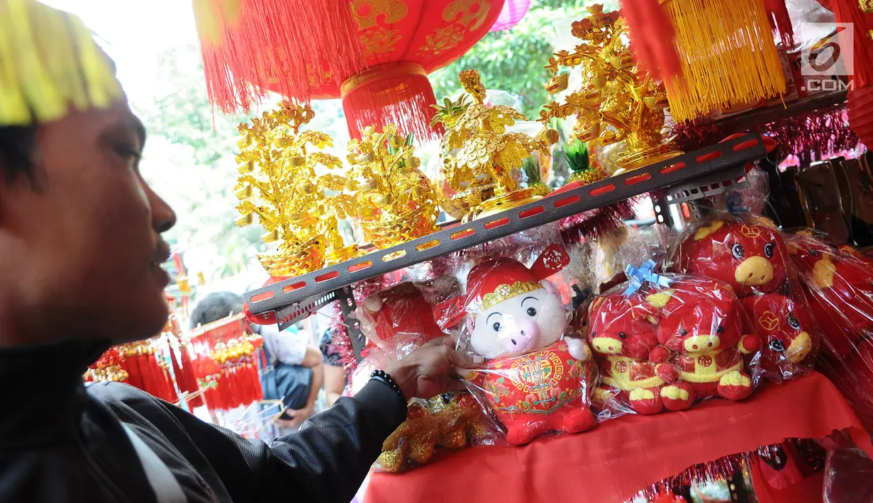 Pedagang merapikan boneka bertema Imlek di kawasan Glodok, Jakarta, Kamis (31/1). Pernak-pernik Imlek bershio babi tanah sudah mulai ramai dijual. (Liputan6.com/Herman Zakharia)