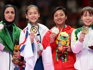 Karateka putri Indonesia, Cokorda Istri Agung Sanistyarani (kedua kanan) menunjukkan medali perunggu usai memenangkan pertandingan di babak final nomor Kumite 55 kg di Arena Karate JCC Senayan, Jakarta, Minggu (26/8). (Liputan6.com/Fery Pradolo)