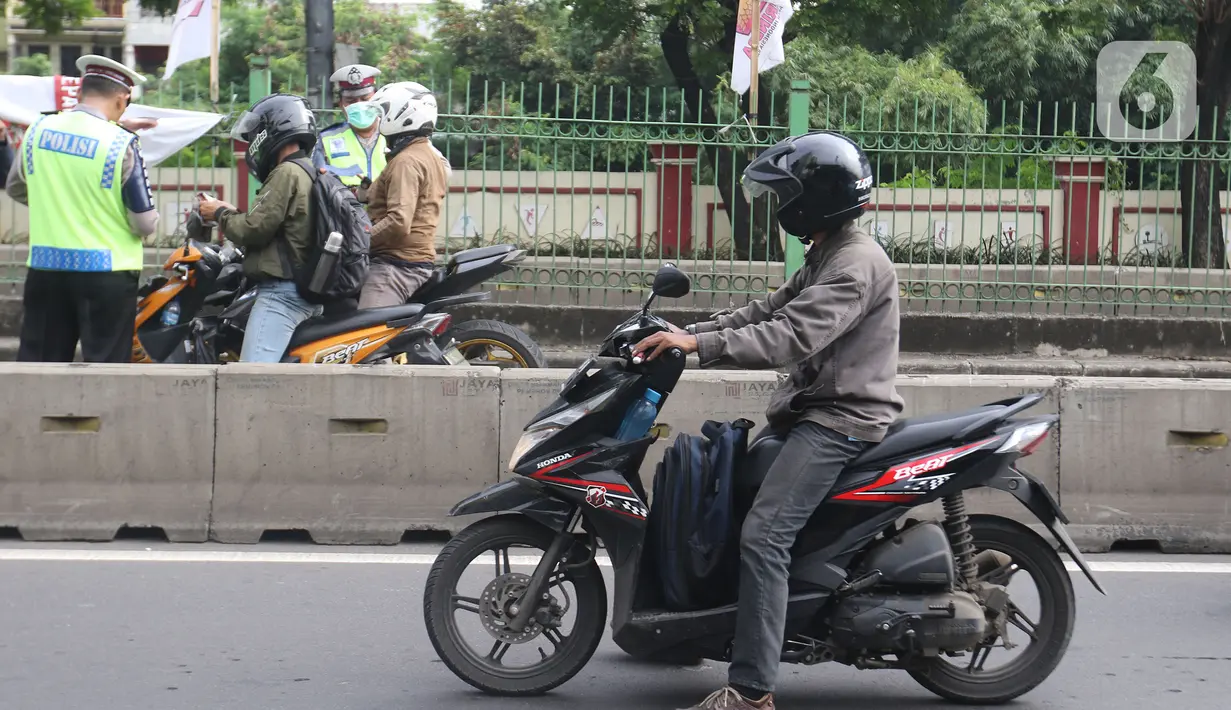 Polisi menilang pengendara sepeda motor yang menerobos jalur Transjakarta di Jalan Sultan Agung, Manggarai, Jakarta, Rabu (12/2/2020). Pengendara kerap melintasi jalur Transjakarta untuk menghindari kemacetan lalu lintas. (Liputan6.com/Herman Zakharia)