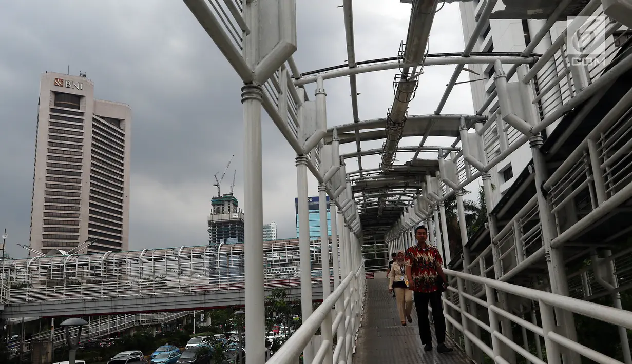 Warga melintasi Jembatan Penyeberangan Orang (JPO) yang rusak di kawasan Dukuh Atas, Jakarta, Rabu (12/12). Rusaknya JPO membahayakan pejalan kaki yang melinatas karena jembatan menjadi licin saat hujan. (Liputan6.com/JohanTallo)