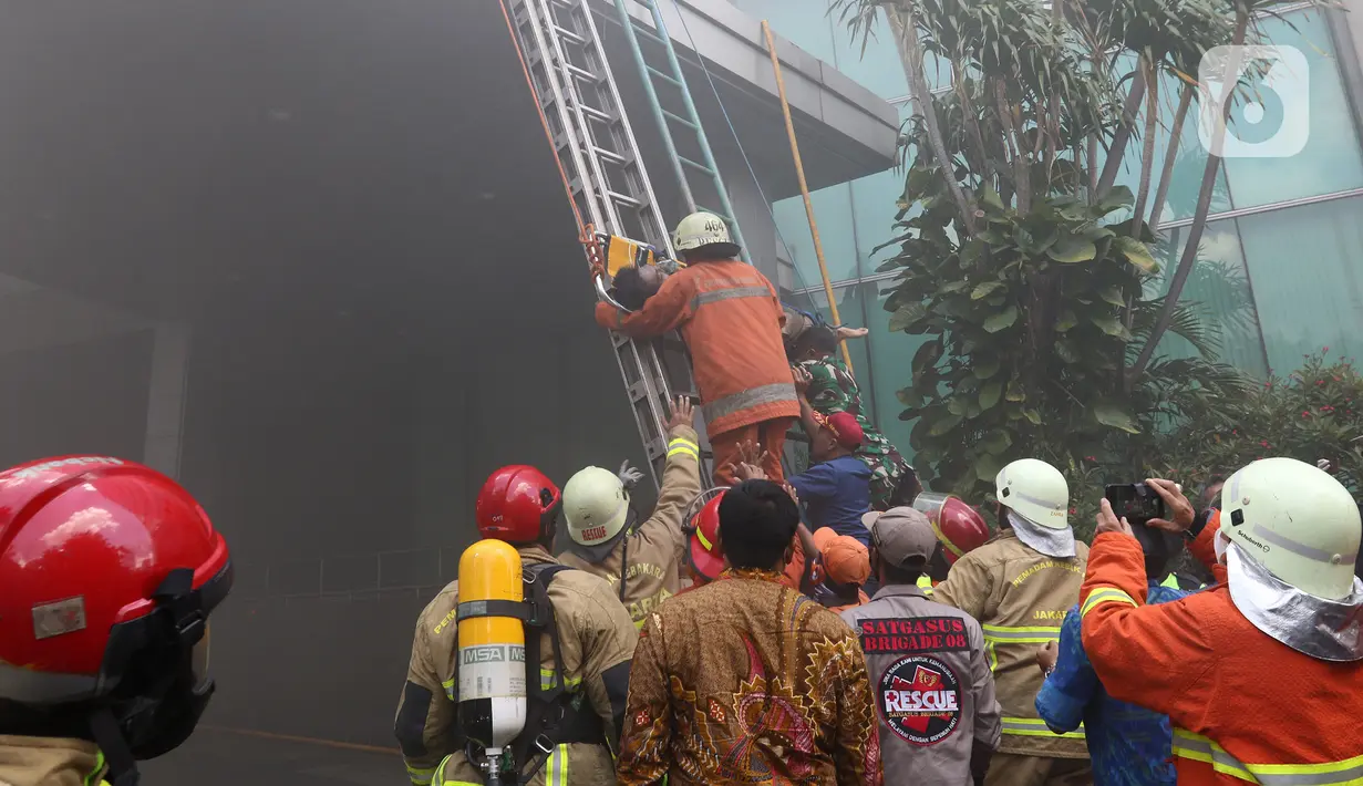 Petugas pemadam kebakaran mengevakuasi korban kebakaran di Gedung Cyber 1, Jakarta, Kamis (2/12/2021). Salah seorang di antara tiga korban atas nama Seto (18) dikabarkan meninggal dunia. (Liputan6.com/Herman Zakharia)