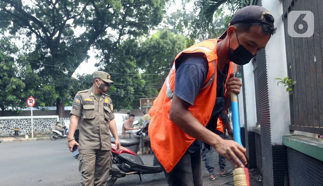 Warga menyapu jalan saat terjaring operasi tertib masker dalam rangka penerapan protokol kesehatan COVID-19 di Jalan Fatmawati, Jakarta, Kamis (10/3/2022). Pelanggar disanksi kerja sosial menyapu jalan atau denda Rp250 ribu dan menandatangani surat pernyataan tak mengulangi.(merdeka.com/Arie Basuki)