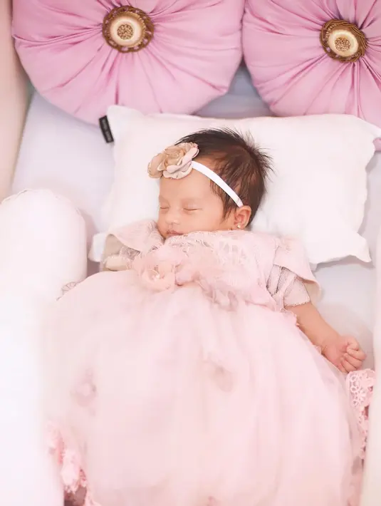 Baby Launa tampil tak kalah menggemaskan dibalut dress pink yang masih terlihat kebesaran, diberi bando dengan detail bunga yang manis. [Foto: Instagram/sabrinaanggraini]