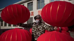 Pekerja membawa lampion yang sudah jadi untuk dijemur jelang perayaan Tahun Baru Imlek di provinsi Hebei, Tingkok (11/1). (AFP Photo/Fred Dufour)