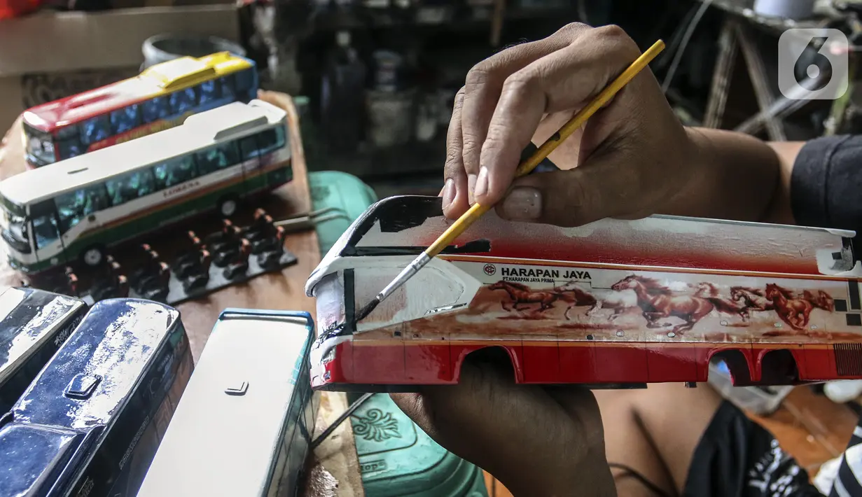 Perajin mengecat miniatur bus di Workshop Belang Bentong, Limo, Depok, Jawa Barat, Jumat (14/1/2022). Kerajinan miniatur bus berbahan baku akrilik dan resin tersebut dipasarkan ke berbagai daerah dengan harga Rp 700 ribu hingga Rp 1 juta per unit. (Liputan6.com/Johan Tallo)
