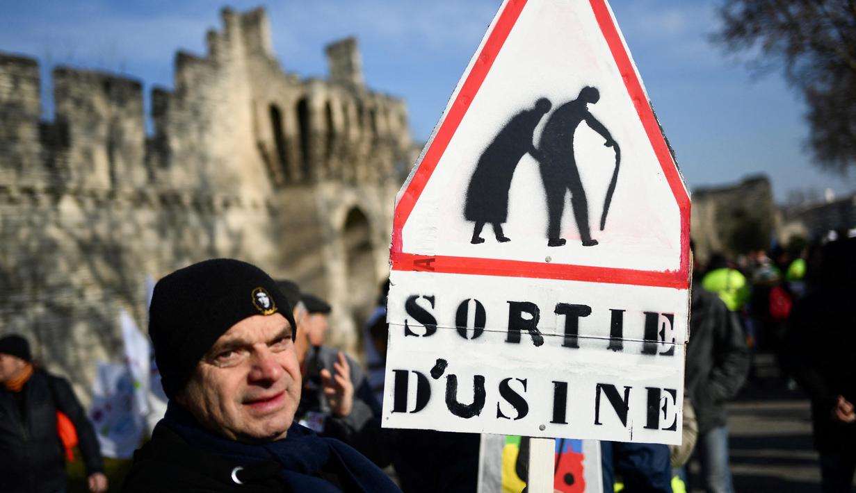 Seorang pria memegang tanda bertuliskan "keluar dari pabrik" selama demonstrasi pada hari kelima demonstrasi nasional yang diselenggarakan sejak awal tahun, menentang perombakan pensiun yang sangat tidak populer, di Avignon, Prancis Selatan, Kamis (16/2/2023). (CHRISTOPHE SIMON/AFP)