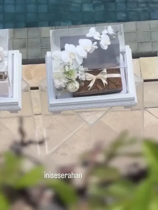 Tampak pula kain batik coklat yang dikemas dengan hiasan pita. Begitu cantik di dalam kotak kacanya. [@iniseserahan]