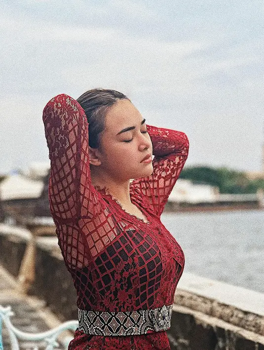 Tampil memesona dengan kebaya jaring warna merah dan belt beraksen batik dalam gaya etnik. (IG: @amandamanopo)