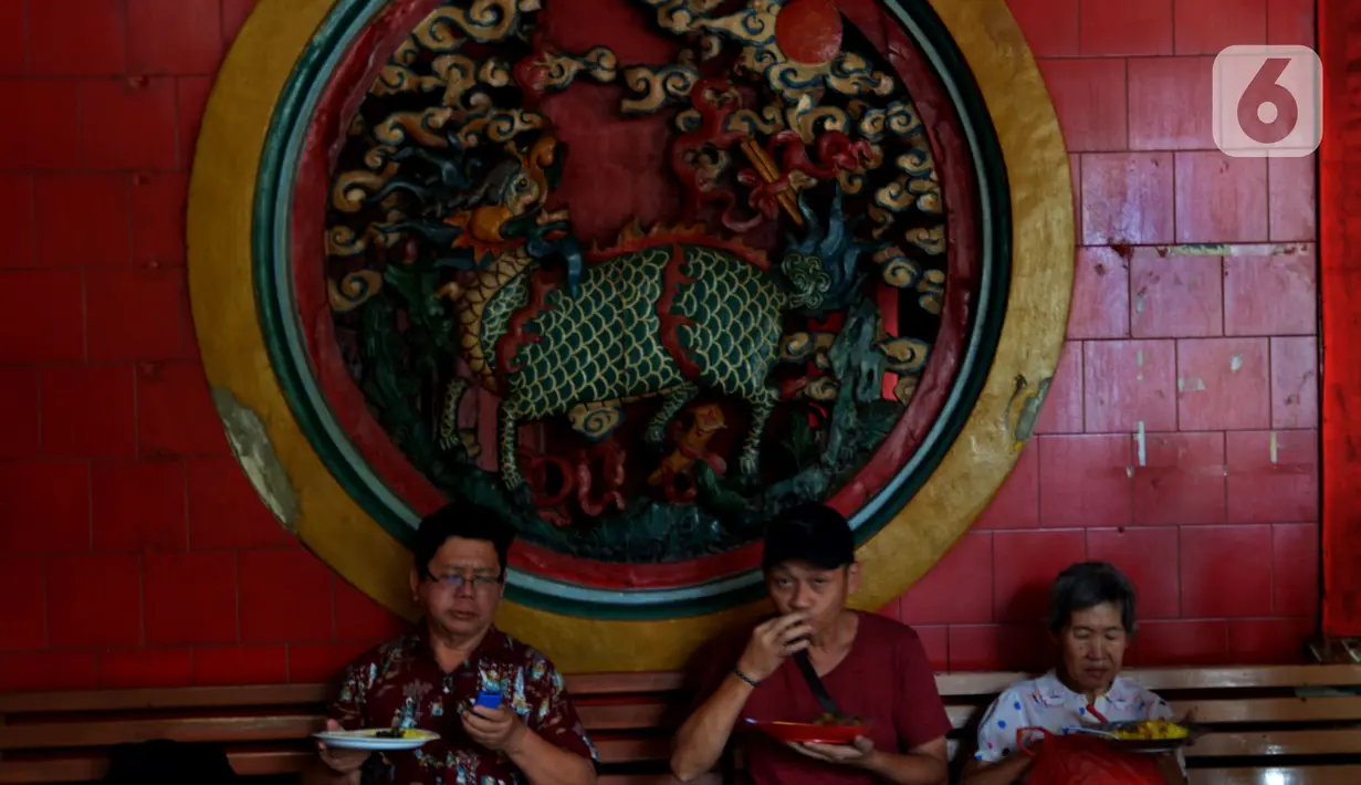 Warga menyantap makan siang di warung nasi kuning Podjok Halal yang berada di Vihara Kim Tek Ie, Petak Sembilan, Jakarta, Selasa (24/12/2019). Para donatur dapat menyumbangkan berbagai makanan untuk warung Podjok Halal. (merdeka.com/Imam Buhori)