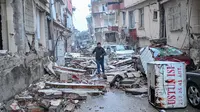 Seorang pria berlari di sepanjang jalan yang dipenuhi puing-puing, di Hatay, sehari setelah gempa berkekuatan 7,8 magnitudo melanda Turki, Selasa (7/2/2023). Tim penyelamat di Turki dan Suriah menghadapi cuaca dingin, gempa susulan, dan bangunan yang runtuh, saat mereka menggali untuk para penyintas yang terkubur oleh gempa bumi yang menewaskan lebih dari 5.000 orang. (BULENT KILIC / AFP)