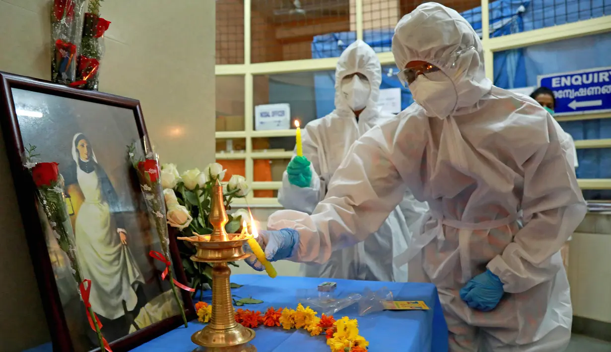 Perawat menyalakan lampu minyak di depan gambar Florence Nightingale saat peringatan Hari Perawat Internasional di Ernakulam Medical College, Kochi, India, Selasa (12/5/2020). Pada tahun ini, Hari Perawat Internasional bertema Nursing the World to Health. (Arun CHANDRABOSE/AFP)