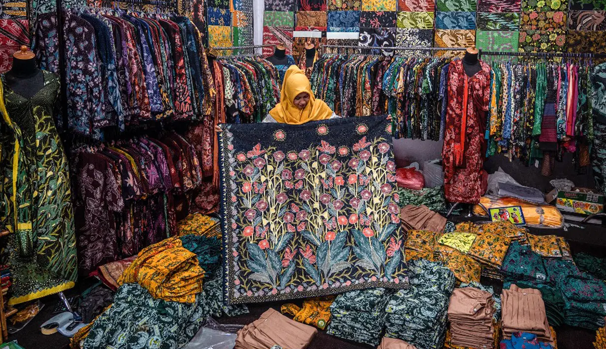 Seorang wanita menunjukkan selembar kain batik di ruang pamer di Sidoarjo, Jawa Timur, Sabtu (1/10/2022). Indonesia akan memperingati Hari Batik Nasional pada 2 Oktober. (JUNI KRISWANTO/AFP)