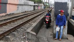 Pengendara melintas di samping kereta yang tengah melintas di kawasan Banjir Kanal Barat, Jakarta, Selasa (20/3). Selain mempersingkat waktu, pengendara beralasan hal itu demi memperpendek jarak tempuh. (Liputan6.com/Arya Manggala)