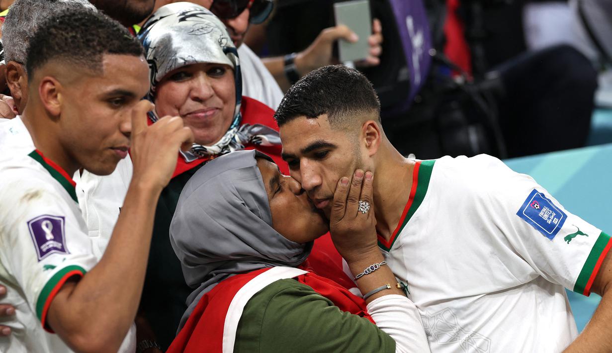 Pemain Maroko, Achraf Hakimi (kanan) merayakan kemenangan bersama ibunya saat laga terakhir Grup F Piala Dunia 2022 melawan Belgia yang berlangsung di Al Thumama Stadium, Qatar, 27 November 2022. (AFP/Fadel Senna)