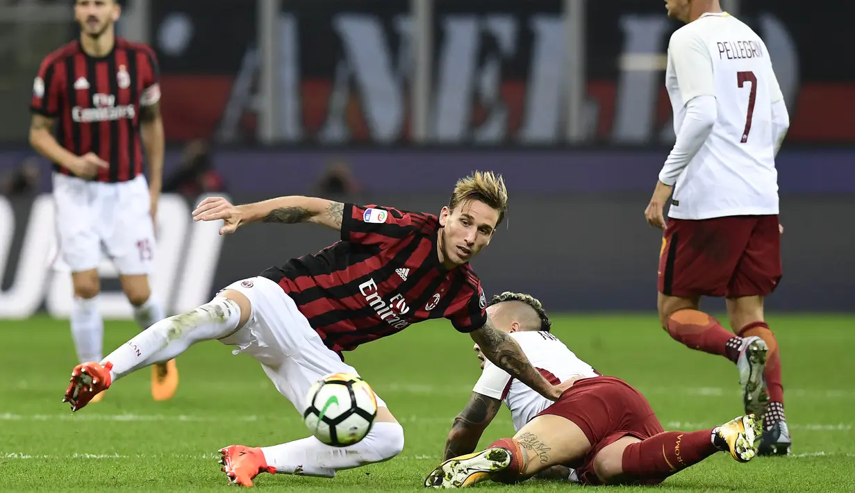 Gelandang AS Roma, Radja Nainggolan, jatuh saat berebut bola dengan gelandang AC Milan, Lucas Biglia, pada laga Serie A Italia di Stadion San Siro, Milan, Minggu (1/10/2017). Milan kalah 0-2 dari Roma. (AFP/Miguel Medina)