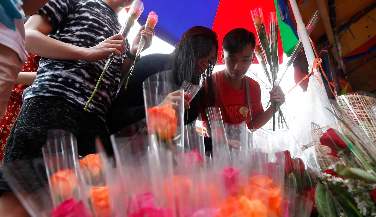 Orang-orang memilih bunga mawar yang dijajakan di sebuah pasar bunga sehari sebelum Valentine Day di Manila, Filipina, Rabu (13/2). Sudah tradisi di seluruh dunia, setiap hari valentine identik dengan pemberian bunga atau coklat. (AP Photo/Bullit Marquez)