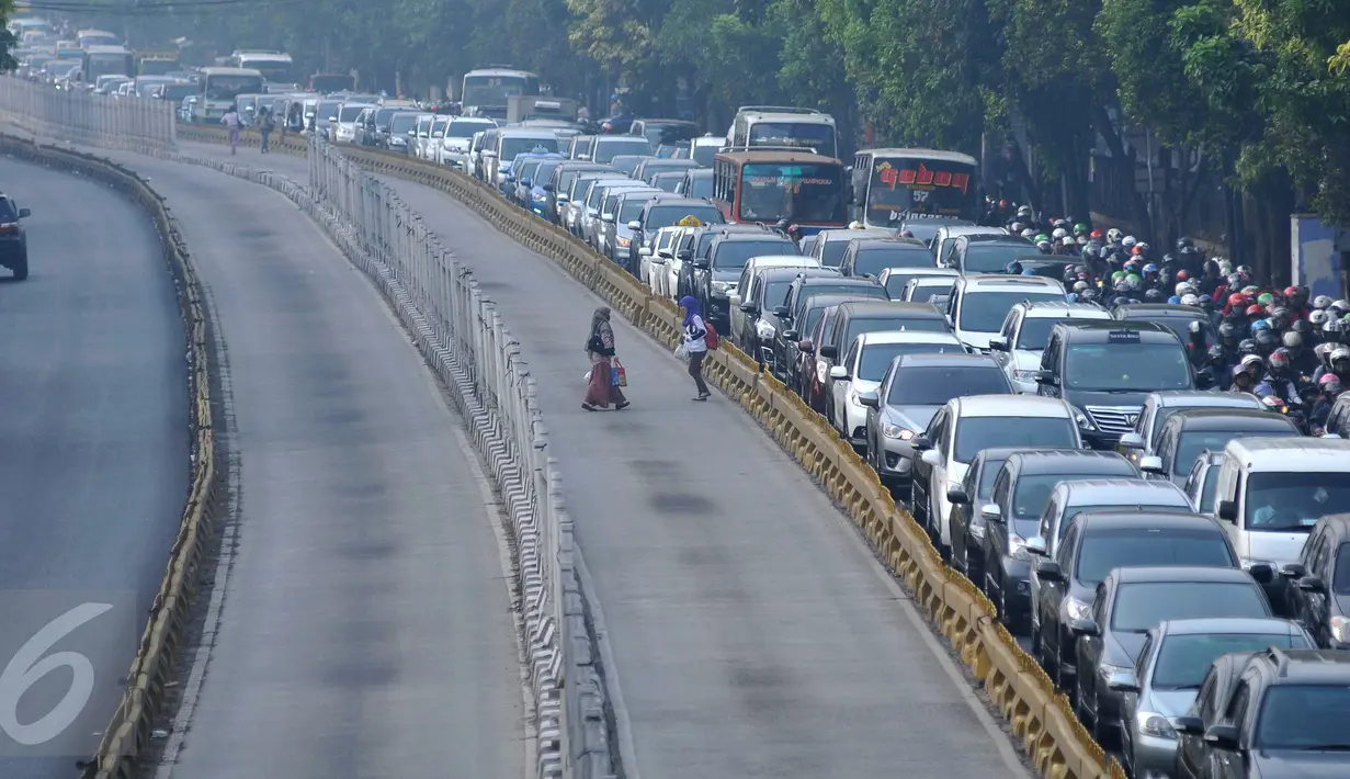 Warga tampak melintasi jalur busway di kawasan Mampang Prapatan, Jakarta, Kamis (29/10). Warga malas menggunakan jembatan penyeberangan dengan alasan malas berjalan jauh. (Liputan6.com/Gempur M Surya)