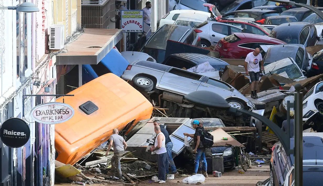 <p>Para pejalan kaki berdiri di samping mobil-mobil yang tertimbun setelah banjir yang mematikan di Sedavi, selatan Valencia, Spanyol timur, pada tanggal 30 Oktober 2024. (Jose Jordan/AFP)</p>