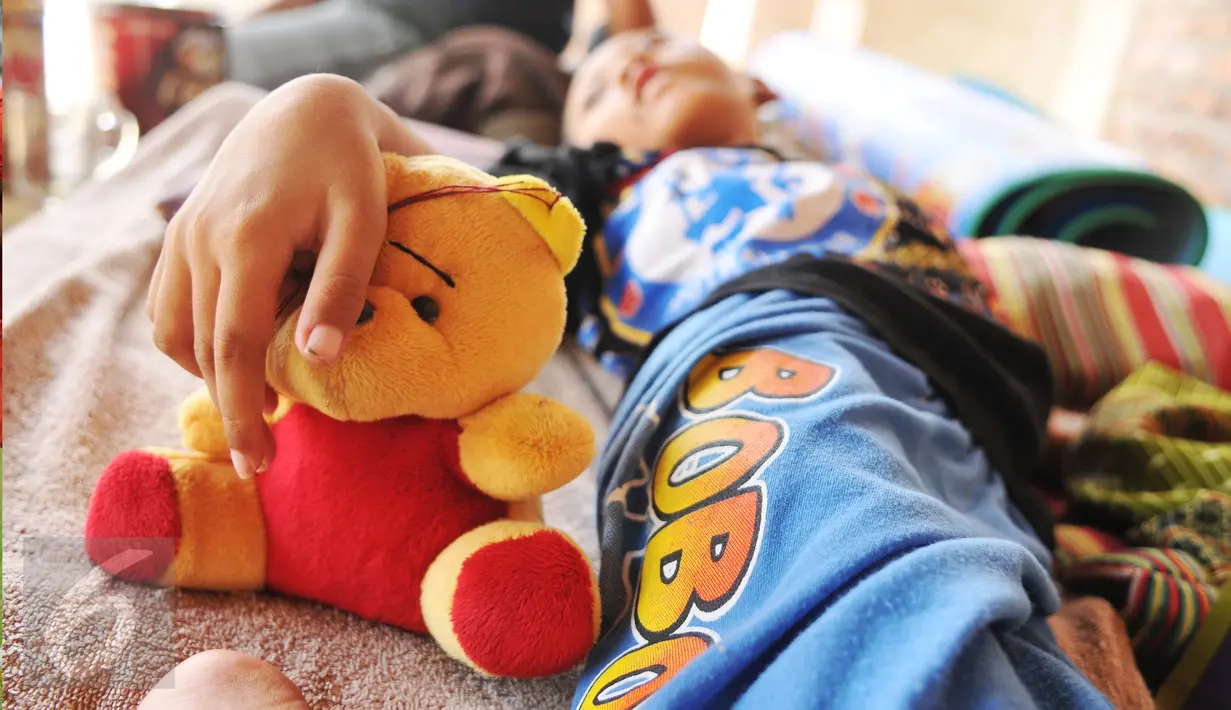 Seorang bocah berumur 8 tahun bernama Indrawan memegang  boneka kesayangannya di Dusun III nomor 21, Kampung Katimaha, Bekasi, Jawa Barat, (11/7). Anak ini mengalami kelainan tulang belakang sejak usia tiga bulan. (Liputan6.com/Gempur M Surya)