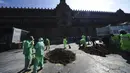 Pekerja kota membersihkan tumpukan tanah yang melambangkan kuburan klandestin buatan orang-orang yang kehilangan anggota keluarga saat menuntut jawaban dari pemerintah di luar Istana Nasional, Mexico City, Meksiko, 13 Desember 2021. (AP Photo/Marco Ugarte)