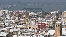 Salju menutupi atap rumah dan bangunan saat hujan salju lebat terjadi di Venesia, Italia, Rabu (28/2). Suhu ekstrim yang melanda negeri tersebut membuat salju tebal menutupi akses jalan transportasi publik dan sejumlah sekolah. (Andrea PATTARO/AFP)