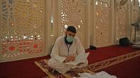 Pria Muslim dengan mengenakan masker saat membaca Alquran saat beritikaf di Masjid Agung Faisal di Islamabad, Pakistan, Kamis (14/5/2020). Itikaf adalah berdiam diri di masjid dengan niat beribadah untuk mendekatkan diri kepada Allah swt pada sepuluh hari terakhir bulan Ramadan. (Aamir QURESHI/AFP)