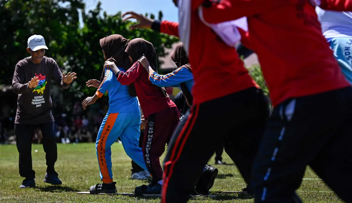 Siswa mengikuti permainan tradisional bakiak pada Festival Permainan Tradisional Anak di Desa Wisata Lubok Sukon, Kecamatan Ingin Jaya, Aceh Besar, Aceh, Sabtu (25/7/2026). (AFP/ Chaideer Mahyuddin)