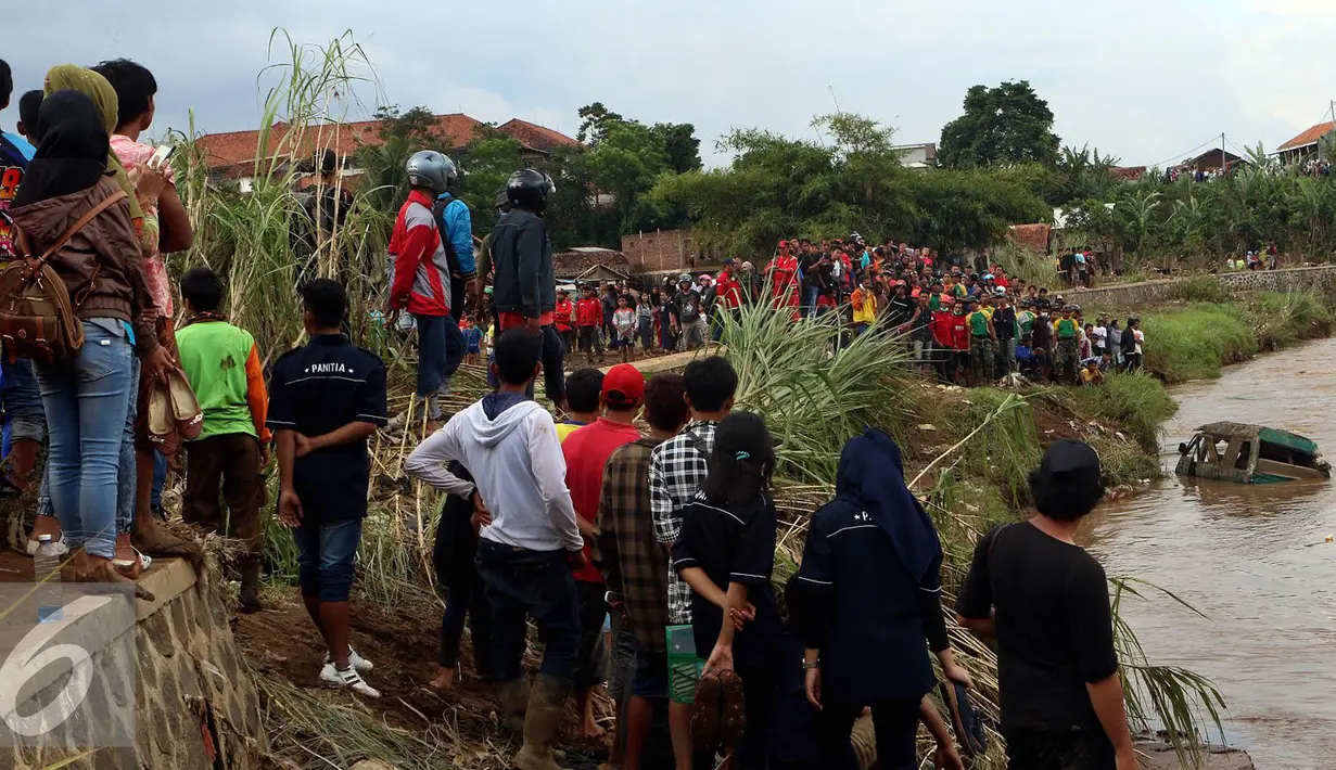 Proses penyisiran bangkai mobil yang diduga terdapat jenazah korban musibah banjir bandang di Cimacan menjadi tontonan warga, Garut (23/9). Data terakhir, korban jiwa mencapai 26 orang dan warga yang hilang 23 orang. (Liputan6.com/Johan Tallo)
