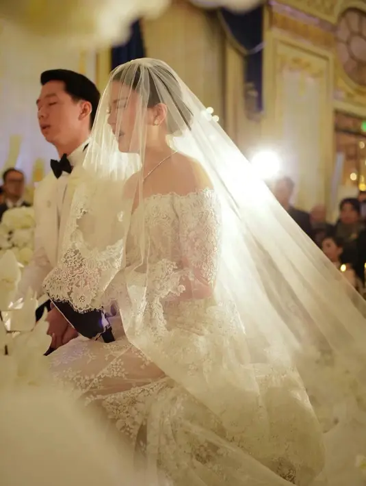 Kevin tampak gagah mengenakan kemeja putih dan celana hitam dihari pernikahannya. Sedangkan mempelai perempuan, Valencia tampak cantik mengenakan gaun putih lengkap dengan vail. [Instagram/diah_kss]