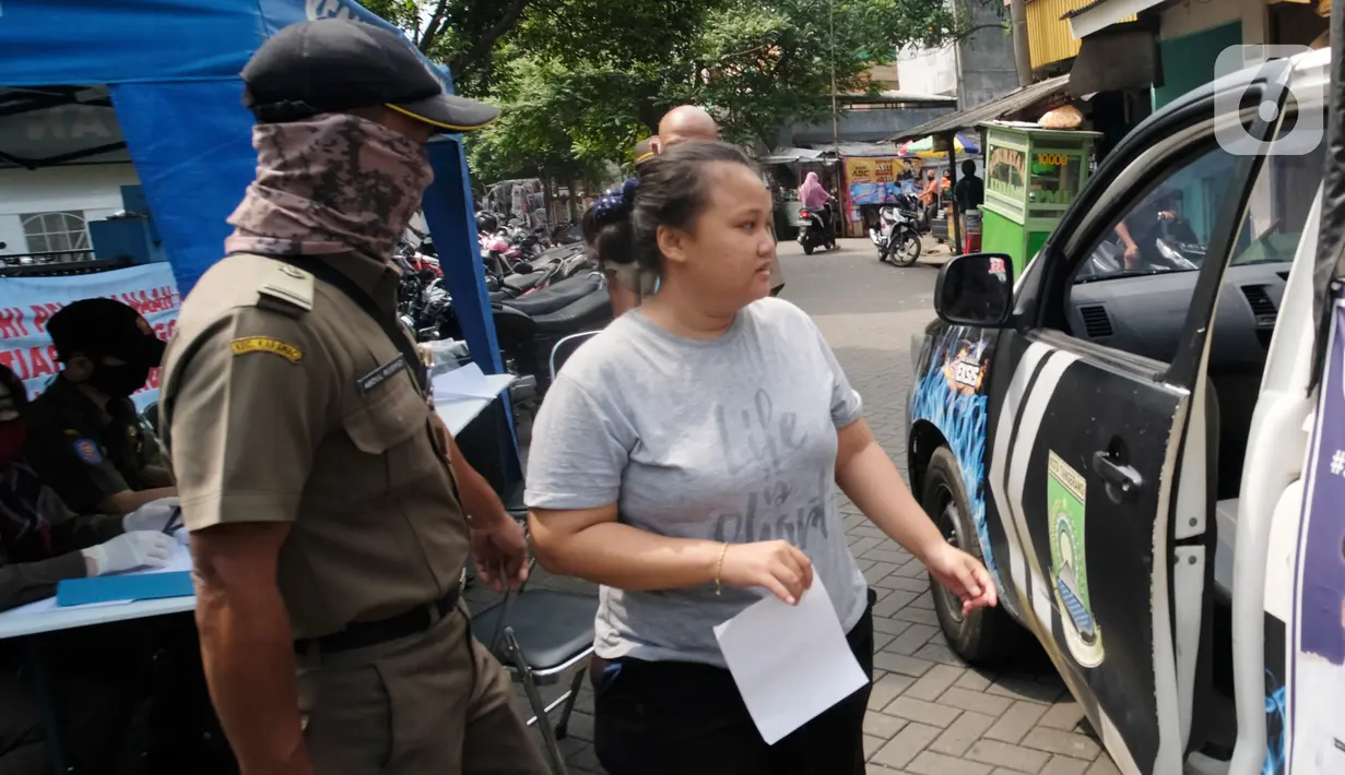 Seorang perempuan yang tidak mengenakan masker bersiap menaiki mobil Satpol PP di Tangerang, Kamis (14/5/2020). Pemkot Tangerang melakukan tindakan bagi pelanggar PSBB dengan membawa mereka ke kantor Kecamatan Karawaci Baru untuk dilakukan rapid test Covid-19. (Liputan6.com/Angga Yuniar)