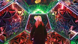 Seorang wanita Martine Basson menikmati seni instalasi lampu karya Amberlights saat festival Canary Wharf Winter Lights di London (16/1). Seni instalasi cahaya karya seniman Amberlights ini berjudul Dazzling Dodecahedron. (Matt Alexander / PA via AP)