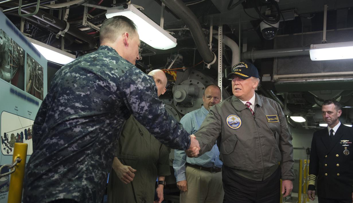 Presiden AS, Donald Trump berjaabat tangan dengan salah satu pasukan saat mengunjungi kapal induk Gerald R. Ford di Newport News, Virginia (2/3). Trump tampak gagah mengenakan jaket panglima tertinggi Navy Seal. (AFP Photo / Saul Loeb)