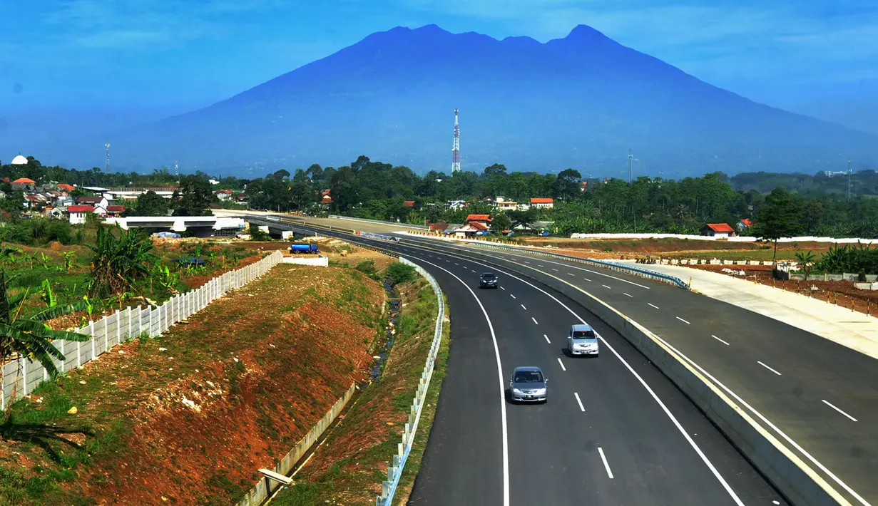 Kendaraan melintasi tol dengan latar belakang Gunung Salak saat Tol Fungsional Bocimi seksi 1 Ciawi-Cigombong dibuka menuju arah Ciawi di kawasan Ciawi Bogor (20/6). (Merdeka.com/ Arie Basuki)