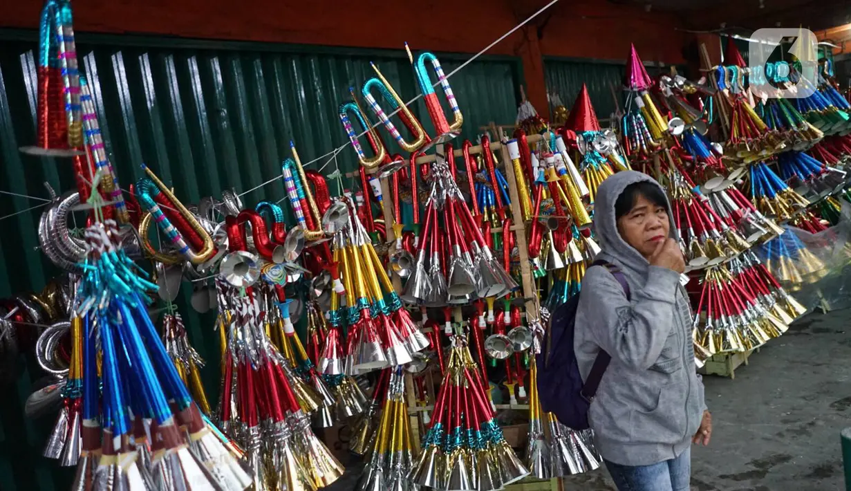 Seorang perempuan berdiri di depan terompet yang dijajakan pedagang di kawasan Glodok, Jakarta, Jumat (27/12/2019). Menjelang pergantian tahun, penjual terompet musiman mulai marak di sejumah kawasan dengan harga jual berkisar Rp5ribu hingga Rp15ribu tergantung model (Liputan6.com/Immanuel Antonius)