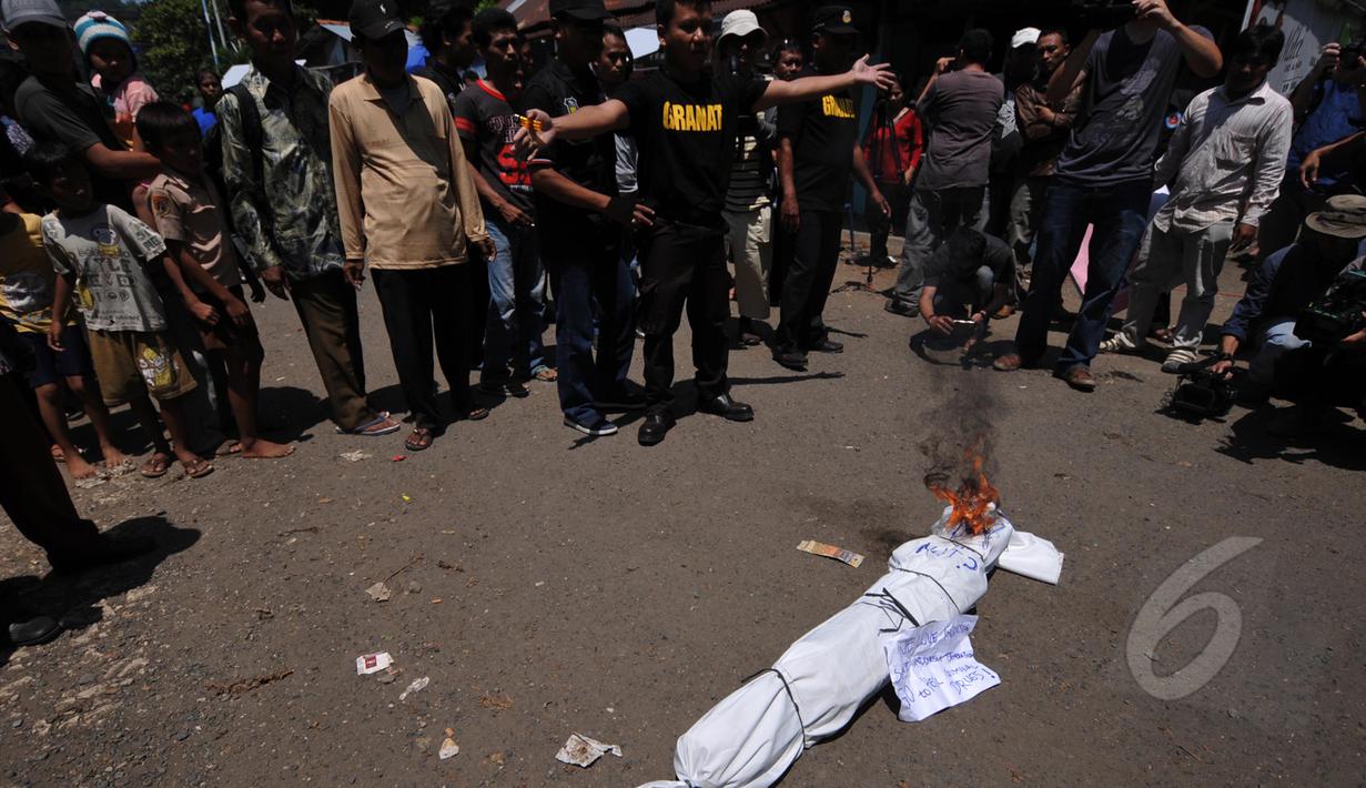 Pegiat Granat membakar pocong sebagai simbol hukuman mati bagi penjahat narkoba saat menggelar aksi  demonstrasi di depan pintu masuk Dermaga Wijaya Pura, Cilacap, Jateng, Jumat (6/3). (Liputan6.com/Johan Tallo)