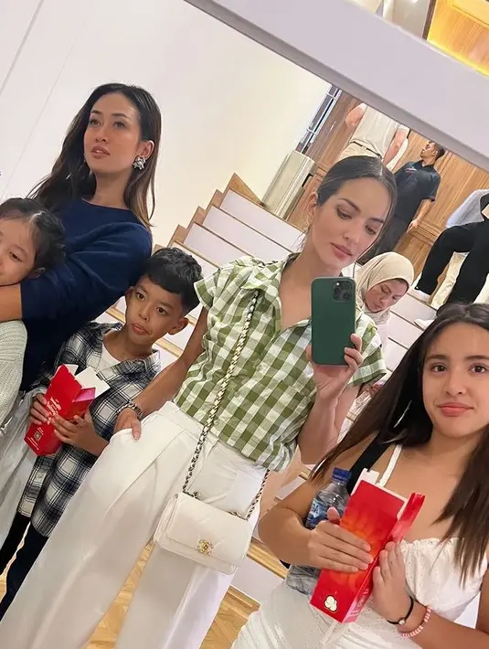 Nia Ramadhani hadir dengan atasan kemeja lengan pendek motif kotak-kotak. Dipadukan celana putih serasi dengan tas Chanel. [@ramadhaniabakrie]