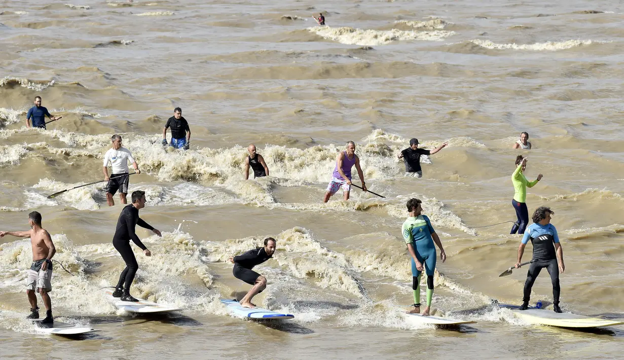Sejumlah warga berselancar di Sungai Dordogne, Saint-Pardon, Prancis (24/7). Fenomena pasang surut besar yang menyebabkan gelombang arus di Sungai Dordogne ini dimanfaatkan warga dan turis unutk berselancar. (AFP Photo/Georges Gobet)