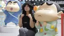 Seorang wanita berekspresi sedih mengikuti model Crayon Shinchan saat berfoto di pameran Joy City, Beijing (5/5/2015). Lima puluh model karakter kartun Jepang dalam berbagai pose dan ekspresi dihadirkan dipameran tersebut. (REUTERS/Jason Lee)
