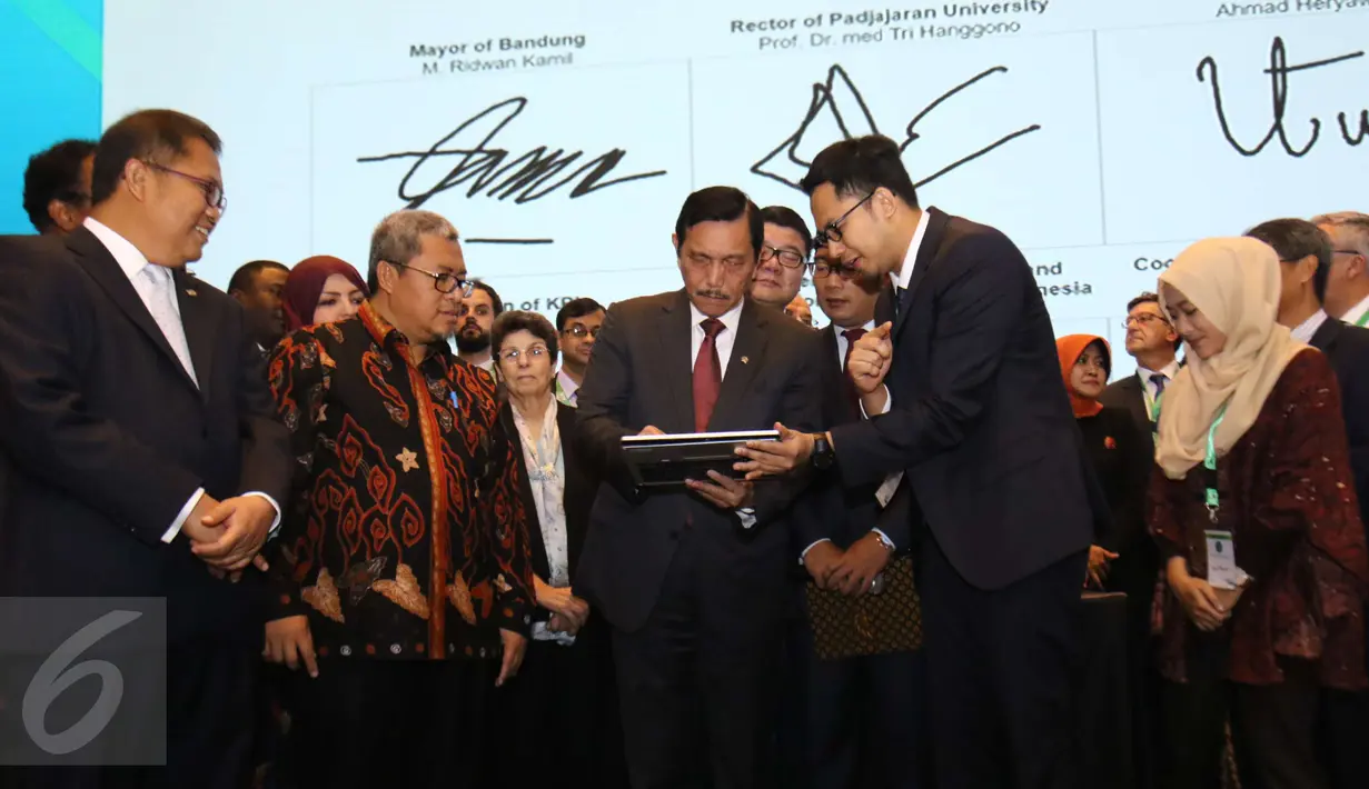 Menko Kemaritiman Luhut Binsar Pandjaitan mencoba fitur  aplikasi saat Konferensi Internasional dan Pertemuan Tahunan ke-5 OIC Broadcasting Regulation Authorities Forum (IBRAF) di Kota Bandung, Rabu (22/2). (Liputan6.com/Helmi Afandi)