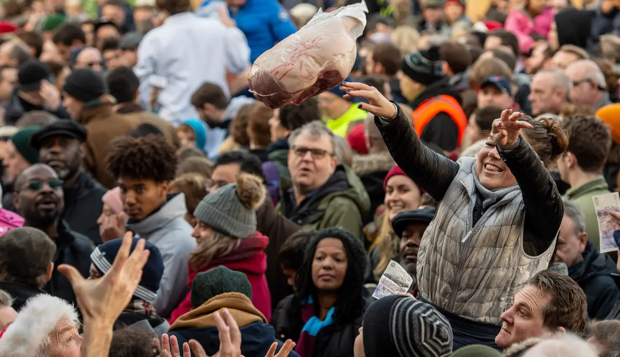 Pedagang melemparkan potongan daging selama tahunan di Smithfield Market, kota London, 24 Desember 2018. Dalam tradisi Natal yang hadir sejak 1800-an, para calon pembeli bisa menawar harga daging tersebut. (NIKLAS HALLE'N/AFP)