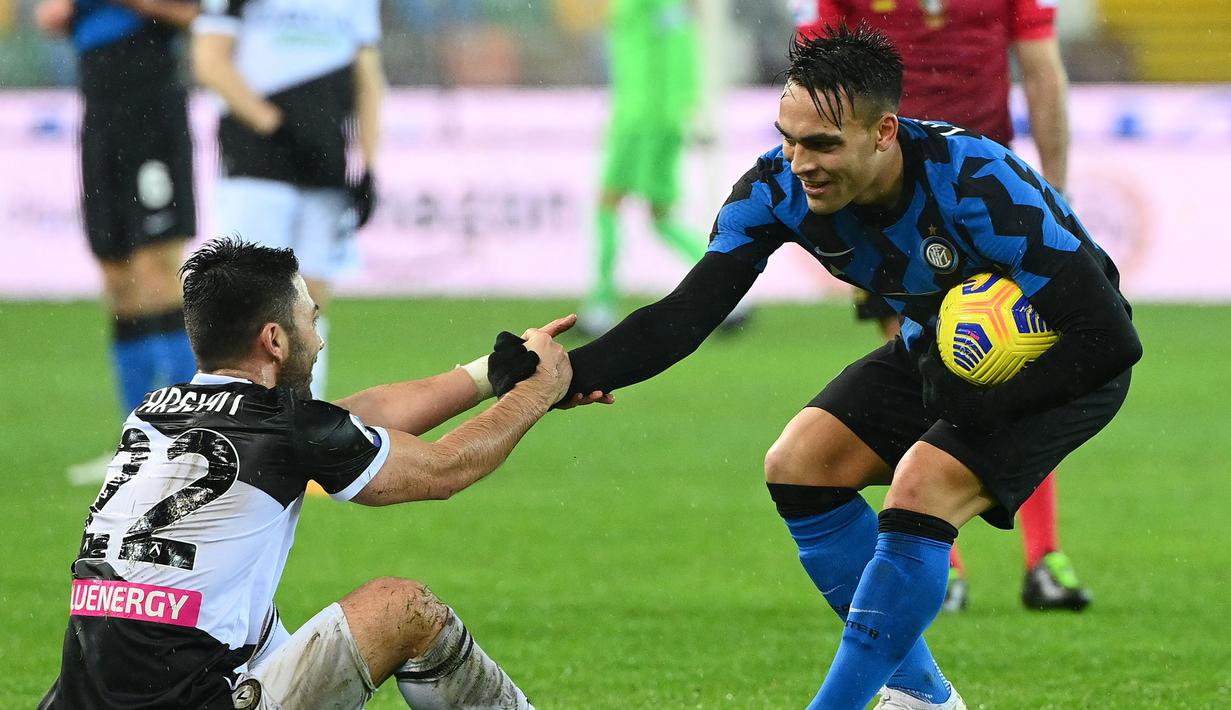 Pemain Inter Milan, Lautaro Martinez (kanan) saat membantu pemain Udinese Tolgay Arslan dalam laga lanjutan Liga Itali 2020/2021 di Friuli stadium, Minggu (24/1/2021) dini hari. (Foto: AFP/Vincenzo Pinto)